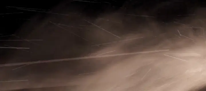 Des traînées et des grains de sable qui volent près de la caméra, sur fond noir